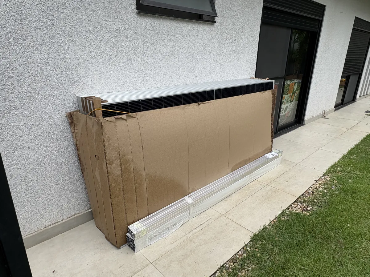 Placas solares na embalagem encostadas na parede junto com trilhos de alumínio